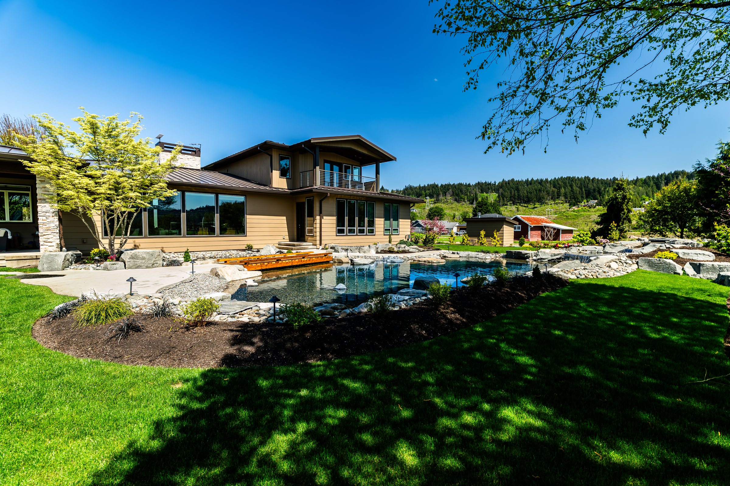 Estate landscape with natural pool, stonework, and layered planting